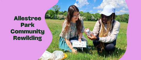 Two young women examine an insect sample container in a meadow, with "Allestree Park Community Rewilding" text overlaid on a pink background.