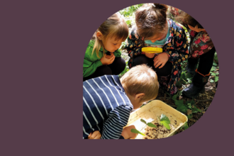 children with magnifying glass crowded round a tub