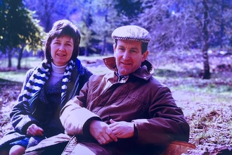 a couple sat on a bench in a park 