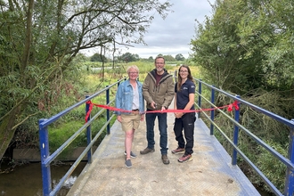 people on bridge cutting ribbon to open