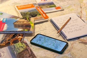 A table with maps for map reading, including a phone with a map and a notepad