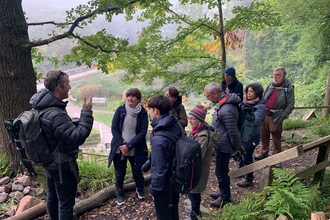 A group of people at Lea Wood standing at a photography workshop, listening to the guide