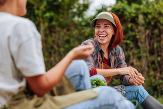 Two people sat together outside, one looking past the camera laughing