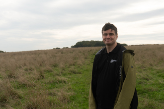 richard standing in a meadow with a grey sky