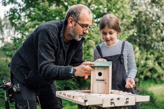 Image of a man helping a girl to make her own bird box