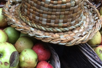 Image of a basket of apple with a straw hat laid on top