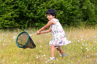 Girl waving a sweep net in a meadow.