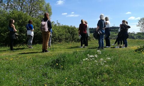 a group of people stood with their back to the camera in a grassy field on a sunny day