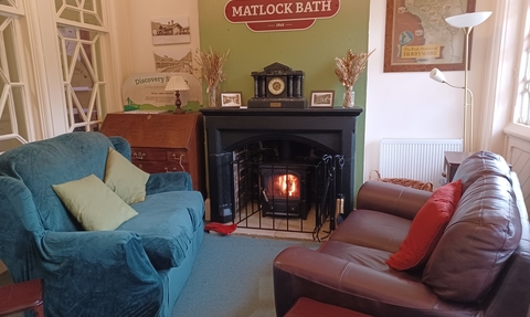 two sofas round a fire in the Whistlestop Community Hub with a big matlock bath sign on the wall