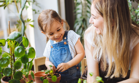 A chlid and their parents potting plants smiling