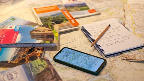 A table with maps for map reading, including a phone with a map and a notepad