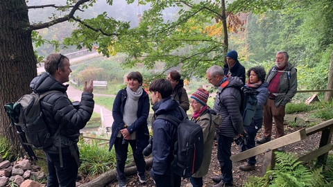 A group of people at Lea Wood standing at a photography workshop, listening to the guide