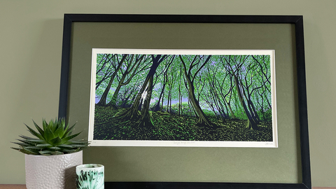a photograph of a framed painting of sunlight through trees