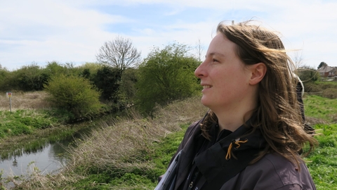 a woman stood next to a canal looking to the left