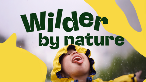 A child in a yellow raincoat joyfully looks up, sticking out their tongue to catch raindrops. Bold green text above reads "Wilder by nature" against a bright yellow abstract background.