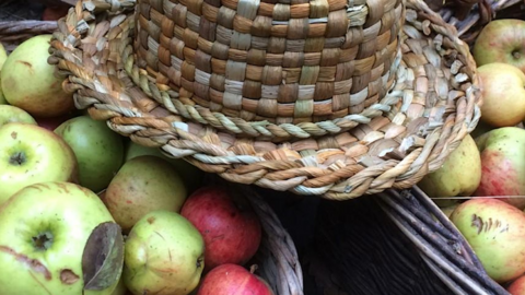 Image of a basket of apple with a straw hat laid on top