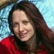 a portrait of Rachel wearing a red top with blue skies behind