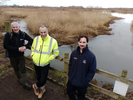 three men stood next to water