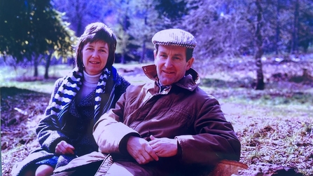 a couple sat on a bench in a park 