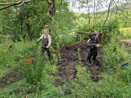 two people digging out a pond