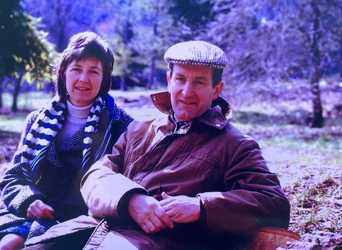 a couple sat on a bench in a park 